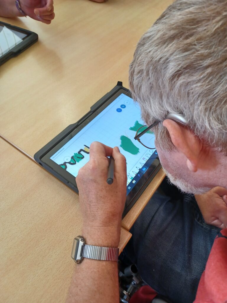 Ein Teilnehmer zeichnet auf dem Tablet mit dem Pen. Wir schauen ihm dabei über die Schulter. Das Bild ist im Kurs #Na Logo!? entstanden.